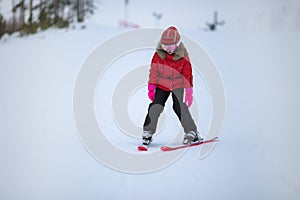 Active adorable preschooler caucasian girl portrait with ski in helmet, goggles and bright suit enjoy winter extreme sport