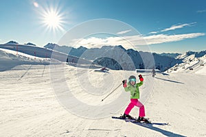 Active adorable preschooler caucasian kid girl portrait with ski in helmet, goggles and bright suit enjoy winter sport activities