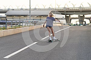 Active adult woman longboarder riding longboard on empty road. Female relax on skateboard after work