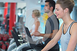 active adults riding stationary bicycles in fitness club