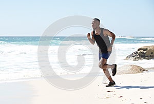 Active african american man running by water on the beach