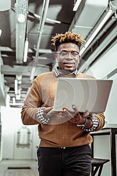 Active African American office worker staring on laptop screen