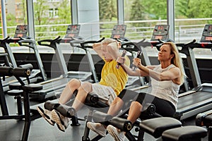 Active aging couple doing abdominal exercises together in modern fitness center, man and woman looks focused.