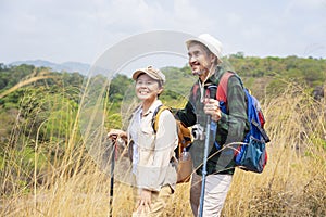 active asian senior couple hiking on the mountain,both of them stop stop walking for a moment,look freedom emotion