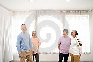 Active Asian senior group mix with man and woman exercise by dancing together at home with relaxing, smiling and laughing.