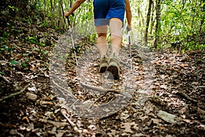 Active athlete climbs up the forest using special equipment for Nordic walking