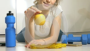 Active athletic sportive woman with towel in sport outfit eating apple after the training