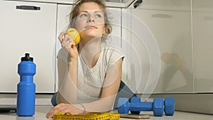 Active athletic sportive woman with towel in sport outfit eating apple after the training