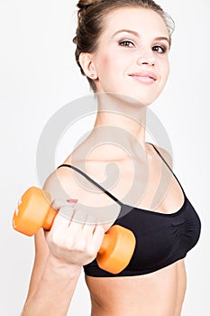 Active athletic woman with dumbbells pumping up muscles biceps. fitness concept