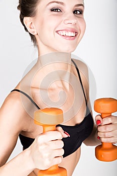 Active athletic woman with dumbbells pumping up muscles biceps. fitness concept