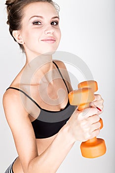 Active athletic woman with dumbbells pumping up muscles biceps. fitness concept