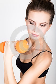 Active athletic woman with dumbbells pumping up muscles biceps. fitness concept