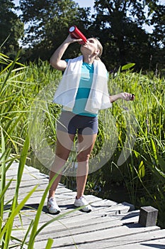 Active beautiful girl having a green sports break, drinking water