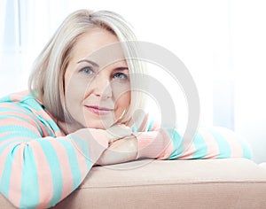 Active beautiful middle-aged woman smiling friendly and looking into the camera at home. Woman's face close up.