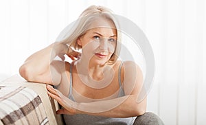 Active beautiful middle-aged woman smiling friendly and looking in camera in living room. Woman`s face close up