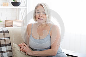 Active beautiful middle-aged woman smiling friendly and looking in camera in living room. Woman`s face close up