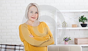 Active beautiful middle aged woman smiling friendly and looking in camera in living room. Woman`s face closeup