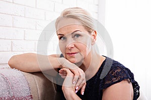 Active beautiful middle-aged woman smiling friendly and looking in camera in living room. Woman`s face closeup. Realistic images