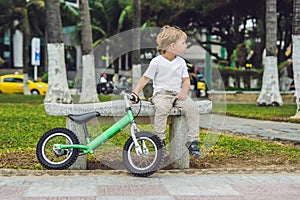 Active blond kid boy and bicycle near the sea. Toddler child dreaming and having fun on warm summer day. outdoors games for childr