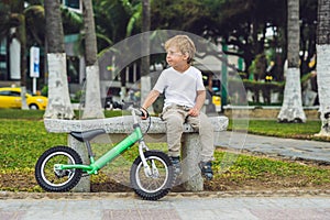 Active blond kid boy and bicycle near the sea. Toddler child dreaming and having fun on warm summer day. outdoors games for childr