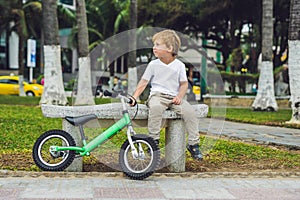 Active blond kid boy and bicycle near the sea. Toddler child dreaming and having fun on warm summer day. outdoors games for childr