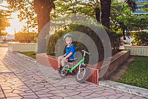 Active blond kid boy driving bicycle in the park near the sea. Toddler child dreaming and having fun on warm summer day. outdoors
