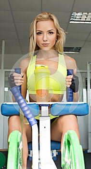 Active blonde woman in sportswear sitting on the sports equipment. Gym. Sports nutrition. Amino acids. look.