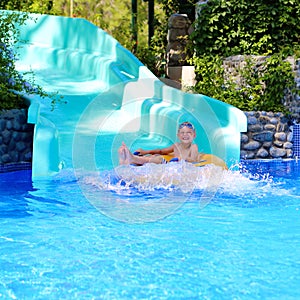 Active boy enjoying water slide in aquapark