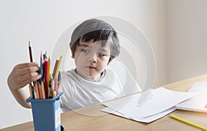 Active boy selecting his favorite pencil colour for painting, School kid using a pencils drawing on white paper, child relaxing at