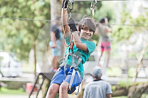 Active brave boy enjoying outbound climbing at adventure park on