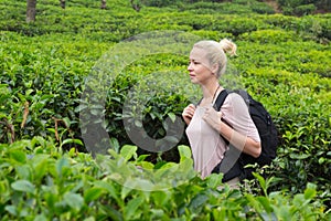 Active caucasian blonde woman enjoing fresh air and pristine nature while tracking among tea plantaitons near Ella, Sri