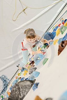 Active caucasian female child is on the climbing wall