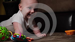 Active caucasian infant baby boy lying on sofa playing with developing toy.