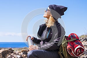 Active caucasian woman resting sit down after a trekking walk -outdor leisure acitivity for healthy people -ocean. view and blue