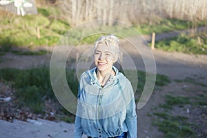 Active cheerful blonde pausing after a run in a park on a sunny