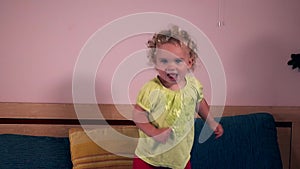 Active child girl jumping on bed in bedroom. Closeup