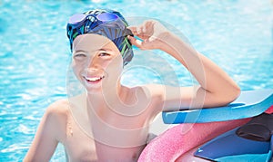 Active child ready to learns professional swimming with pool board, swim noodles and fins.