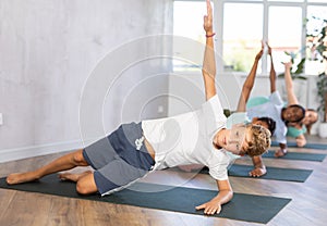 Active children exercising during yoga class in fitness center - vakrasana pose