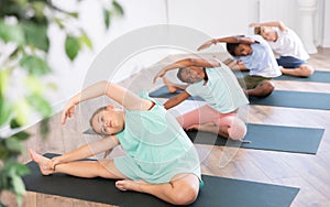 Active children exercising during yoga class in fitness center - vakrasana pose photo