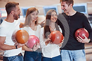 Active conversation. Young cheerful friends have fun in bowling club at their weekends