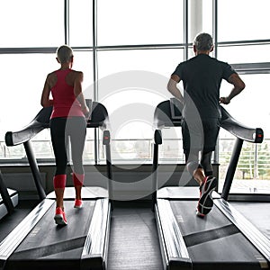 Active couple exercising on treadmills in sports center