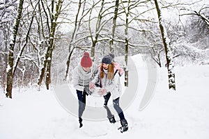 Active couple of teenagers making snowman