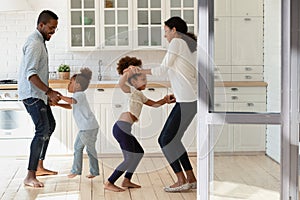 Active crazy african ethnicity family couple dancing with little children.