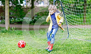 Active cute little kid boy playing soccer and football and having fun