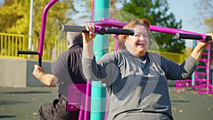 Active elderly couple doing sports on the simulator outdoors. Exercising outdoors in a park or garden in a health and