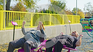 Active elderly couple doing sports on the simulator outdoors. Exercising outdoors in a park or garden in a health and