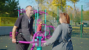 Active elderly couple doing sports on the simulator outdoors. Exercising outdoors in a park or garden in a health and