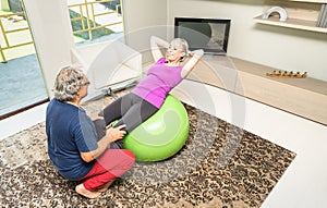 Active elderly couple at fitness training with swiss ball at home