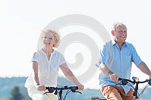 Active elderly couple riding bicycles together in the countryside