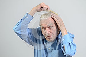 Active elderly man combing his hair with a comb
